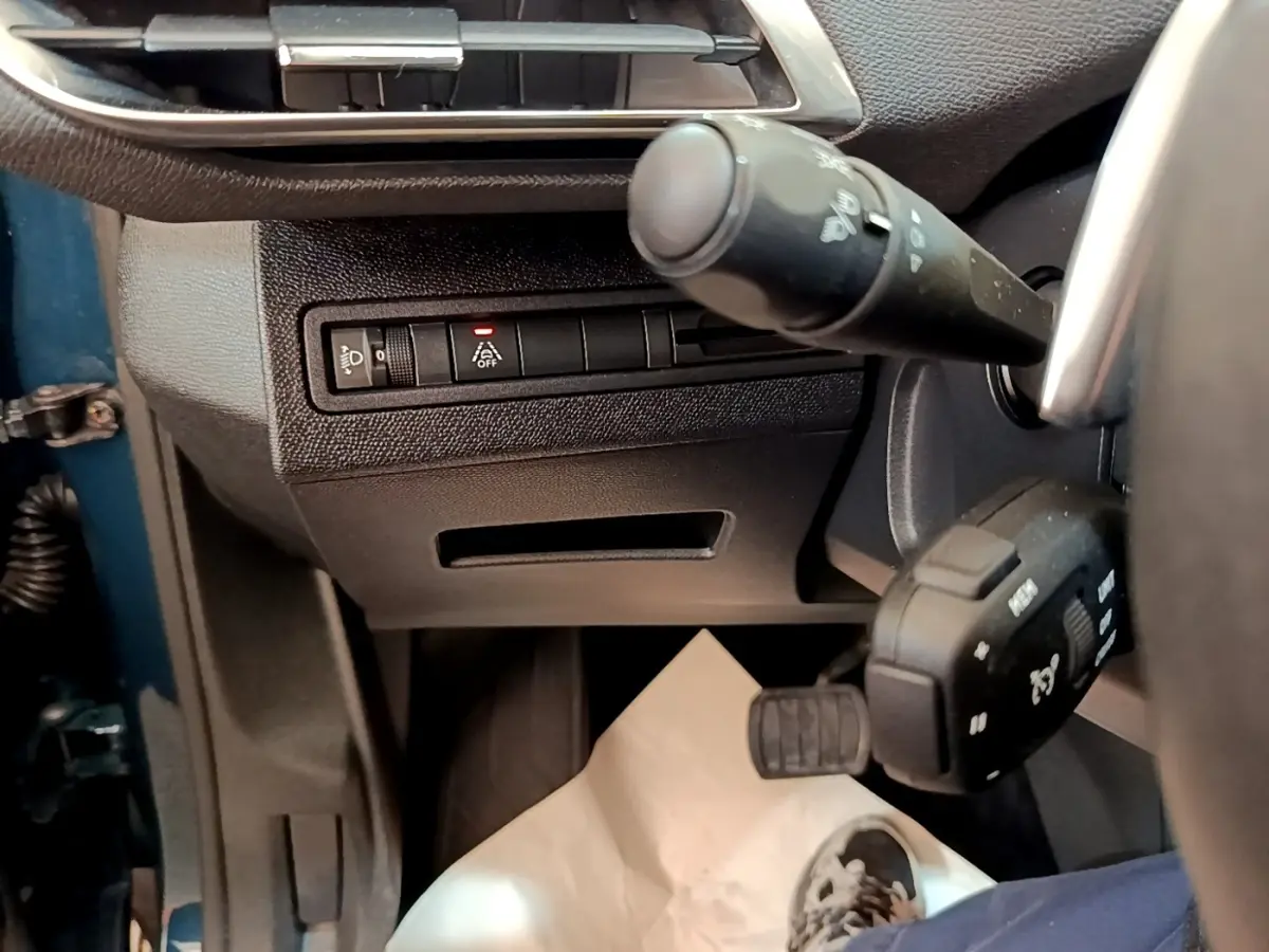 Détail intérieur côté gauche du tableau de bord Peugeot 5008 bleu, avec commandes d’éclairage et volant partiel visible.