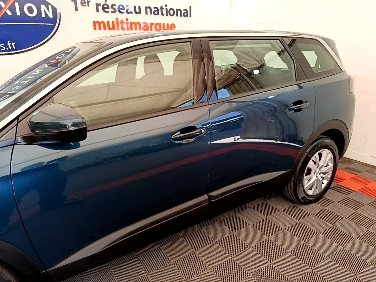 Vue latérale côté droit d'un Peugeot 5008 bleu 2021 avec jantes alliage et rétroviseurs ton caisse.