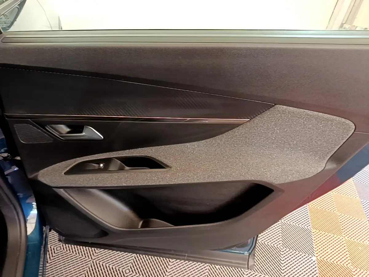 Vue intérieure de la porte avant gauche d’un Peugeot 5008 bleu, avec garniture tissu et plastique noir.