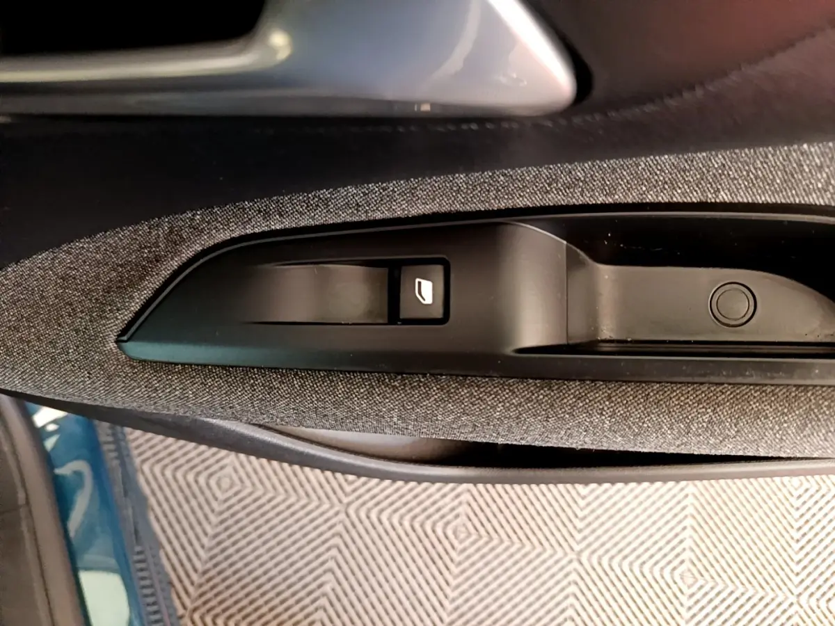 Gros plan sur la commande de lève-vitre côté conducteur dans l’habitacle du Peugeot 5008 bleu.
