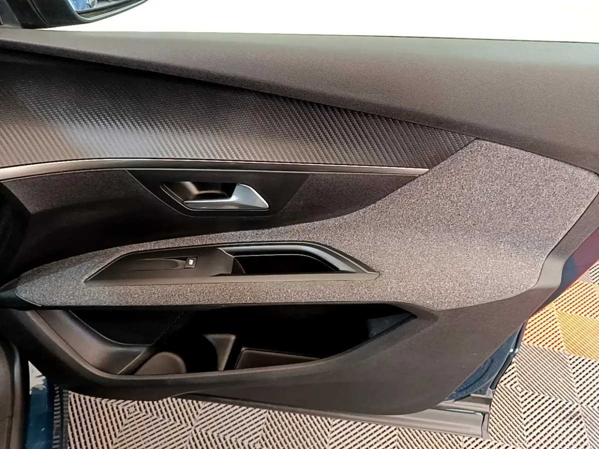 Vue intérieure côté gauche de la porte avant d’un Peugeot 5008 bleu, avec habillage tissu et poignée argentée.