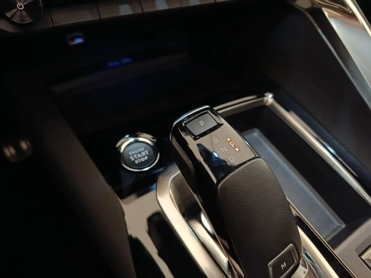 Gros plan sur la commande de boîte automatique noire et bouton start/stop dans l’habitacle du Peugeot 3008 rouge.