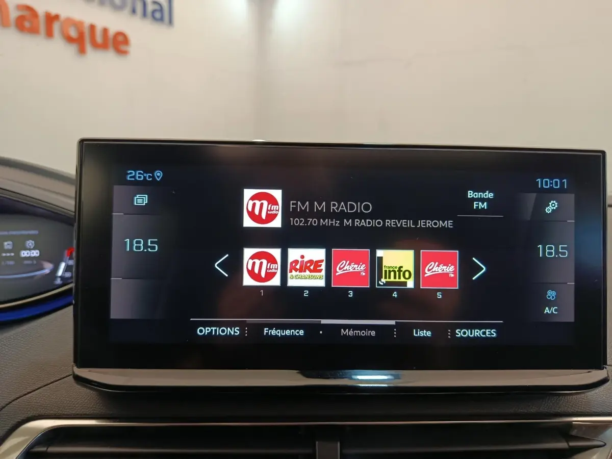 Écran tactile central affichant la radio FM dans l'habitacle du Peugeot 3008 rouge, vue intérieure frontale.
