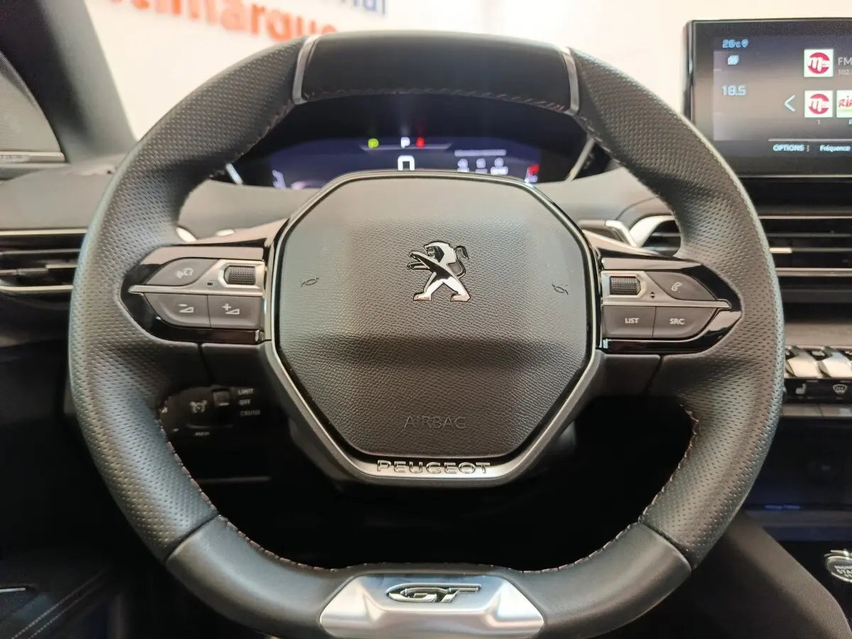 Vue rapprochée du volant cuir perforé Peugeot 3008 GT Pack 2022 avec commandes multifonctions et logo central.