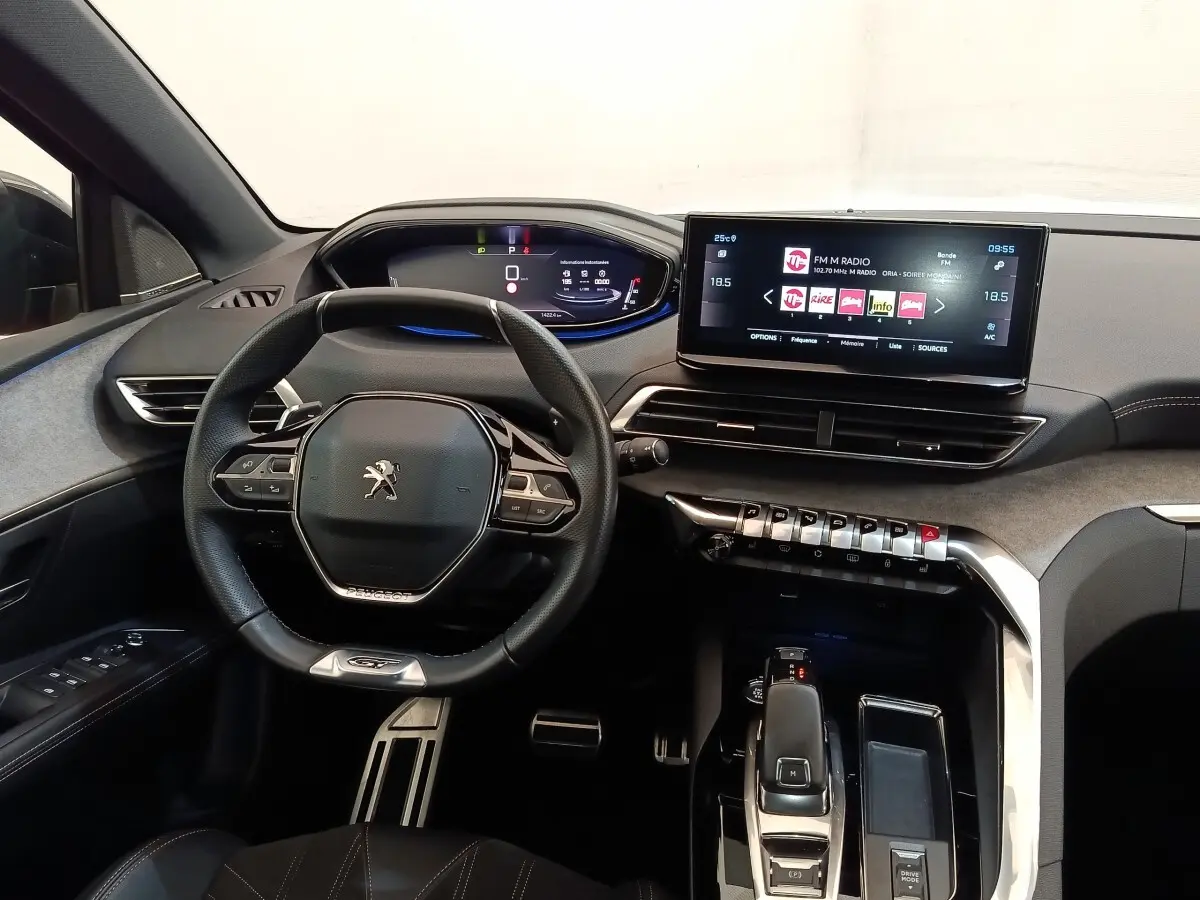 Vue intérieure avant du tableau de bord du Peugeot 3008 GT Pack 2022 avec volant compact et écran tactile central.