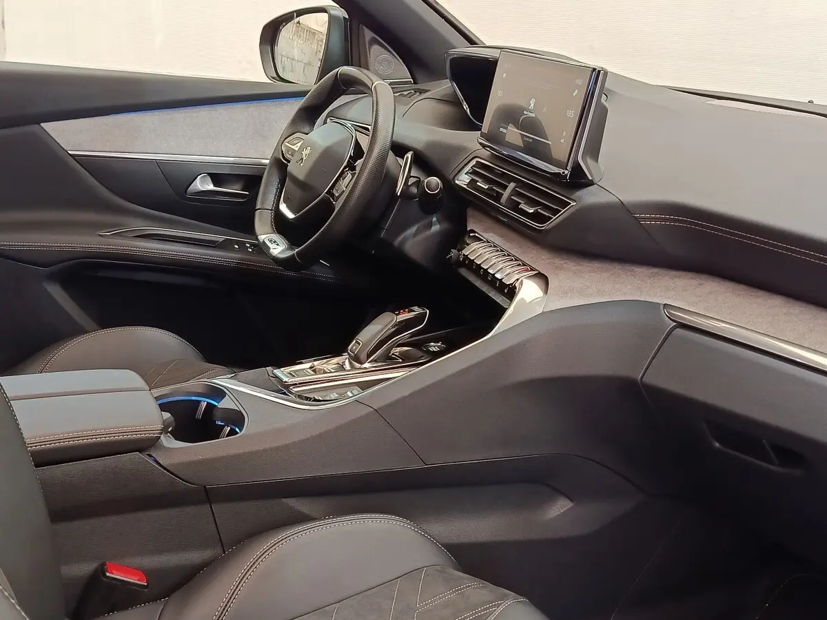 Vue intérieure côté conducteur du Peugeot 3008 GT Pack 2022, tableau de bord moderne avec écran tactile et volant cuir noir.