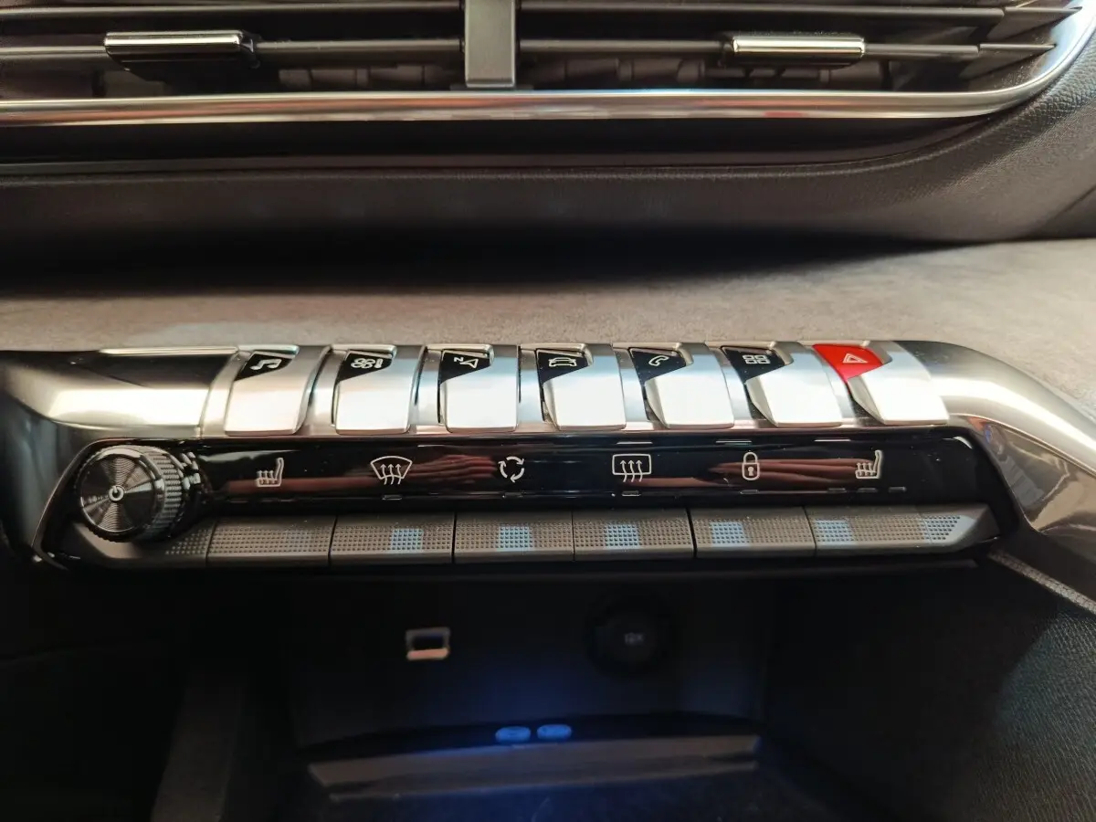 Gros plan sur la console centrale du Peugeot 3008 rouge 2022, montrant les commandes climatisation et boutons piano chromés.