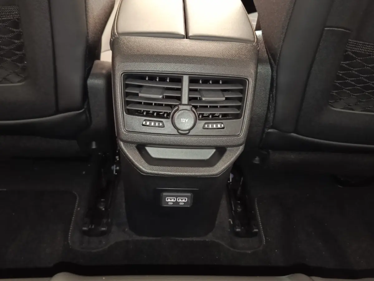 Vue rapprochée de la console centrale arrière noire du Peugeot 3008 2022 avec ventilation et prises USB visibles.