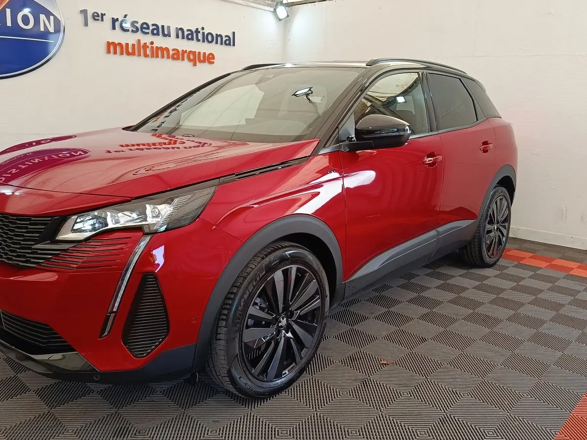 Peugeot 3008 rouge vue 3/4 avant droit, avec jantes noires et toit noir contrasté en intérieur showroom.