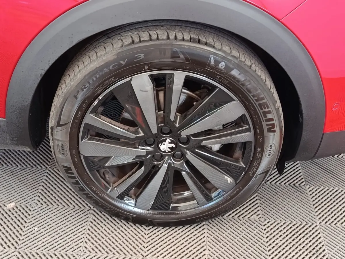 Gros plan sur la roue avant droite noire et argentée du Peugeot 3008 rouge, avec pneu Michelin visible.