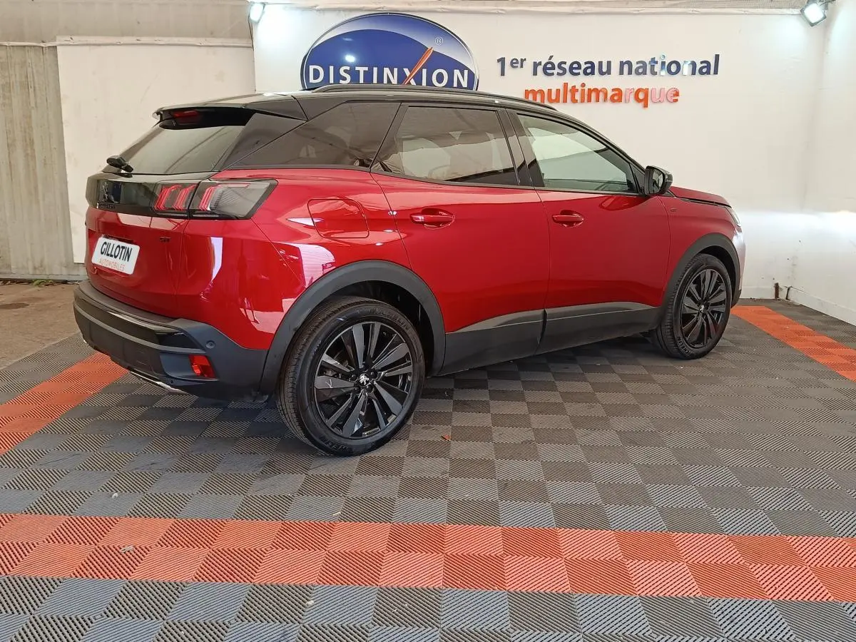 Peugeot 3008 rouge vue 3/4 arrière droit, toit noir et jantes alliage noires dans showroom.