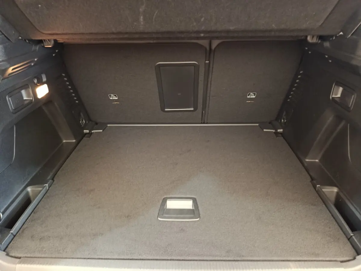 Coffre ouvert vu de face du Peugeot 3008 rouge 2022, espace de rangement avec plancher plat et éclairage intérieur.
