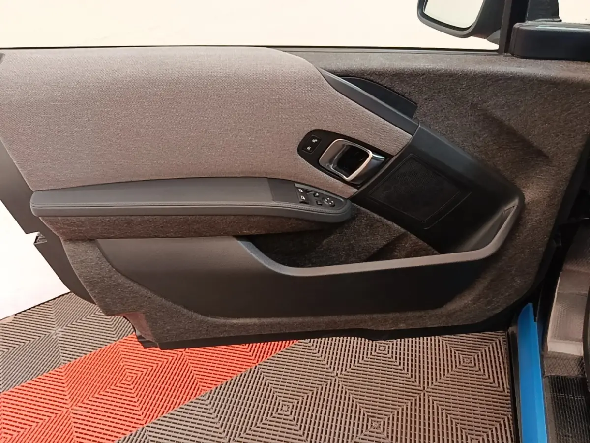 Gros plan sur la porte intérieure côté gauche de la BMW i3 120 Ah Atelier noire, montrant les commandes et le revêtement tissu.