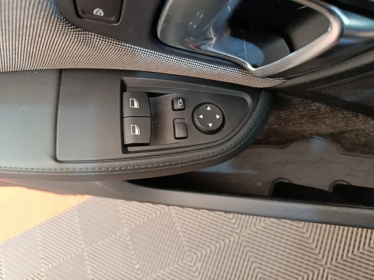Vue rapprochée du panneau de commandes des vitres côté gauche intérieur d’une BMW i3 noire 2020.