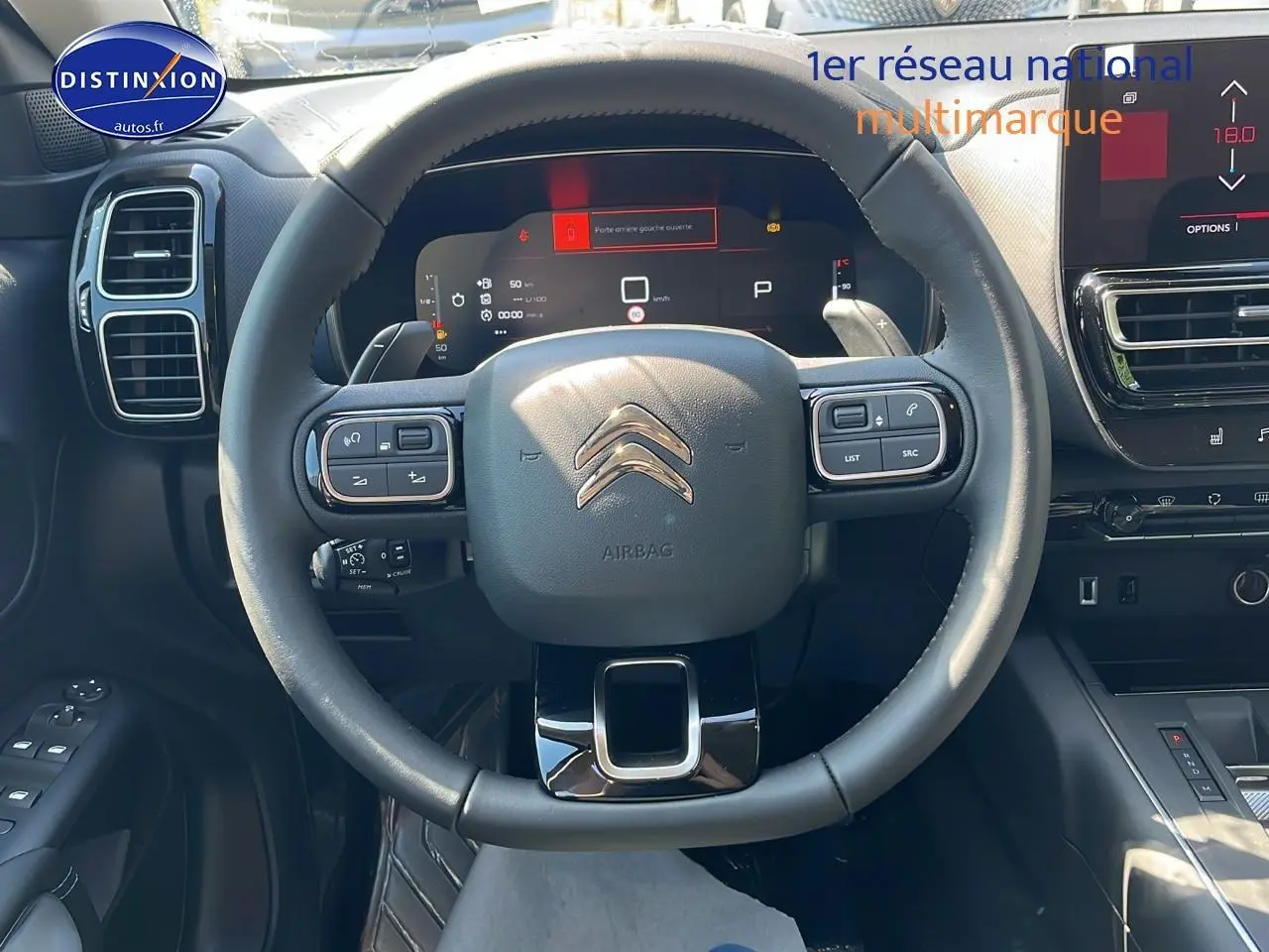 Vue intérieure centrée sur le volant noir du Citroën C5 Aircross 2025 avec tableau de bord digital et écran tactile.