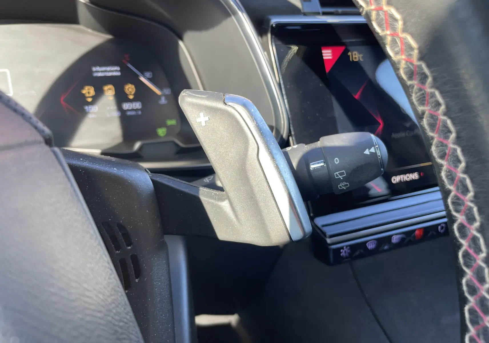 Gros plan sur la palette de changement de vitesse droite et le tableau de bord numérique du DS7 gris Artens, intérieur moderne avec écran tactile.