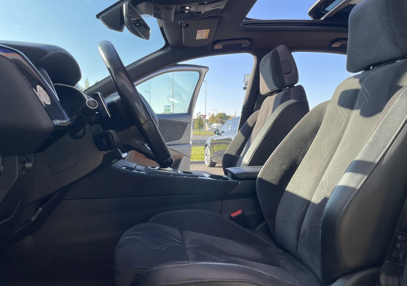 Vue intérieure côté conducteur du DS7 2018, sièges gris noir en alcantara avec toit ouvrant panoramique visible.