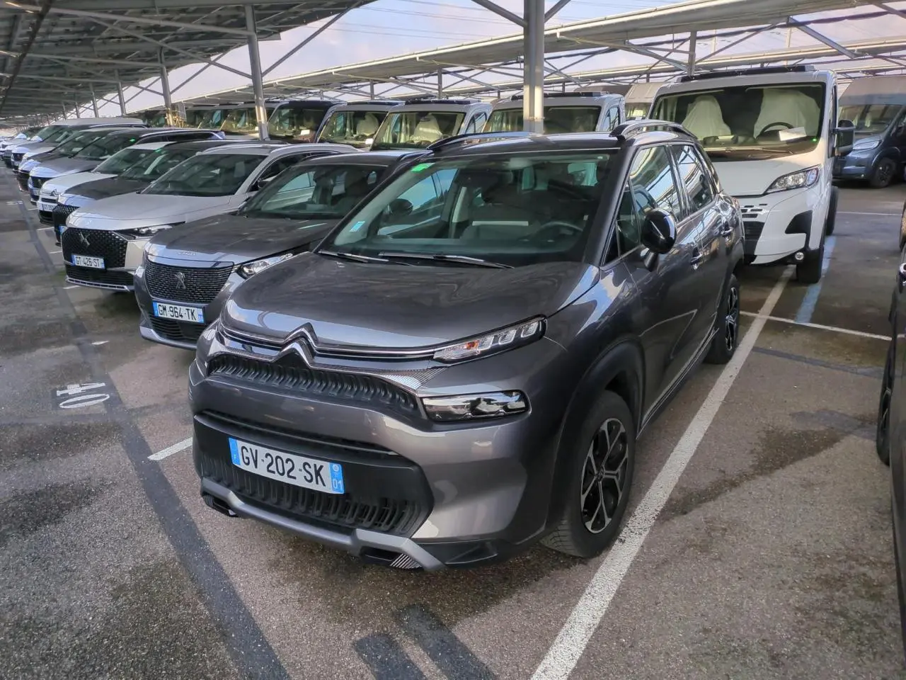 Citroën C3 Aircross gris foncé vue 3/4 avant droit, avec jantes alliage et toit noir brillant sous abri.