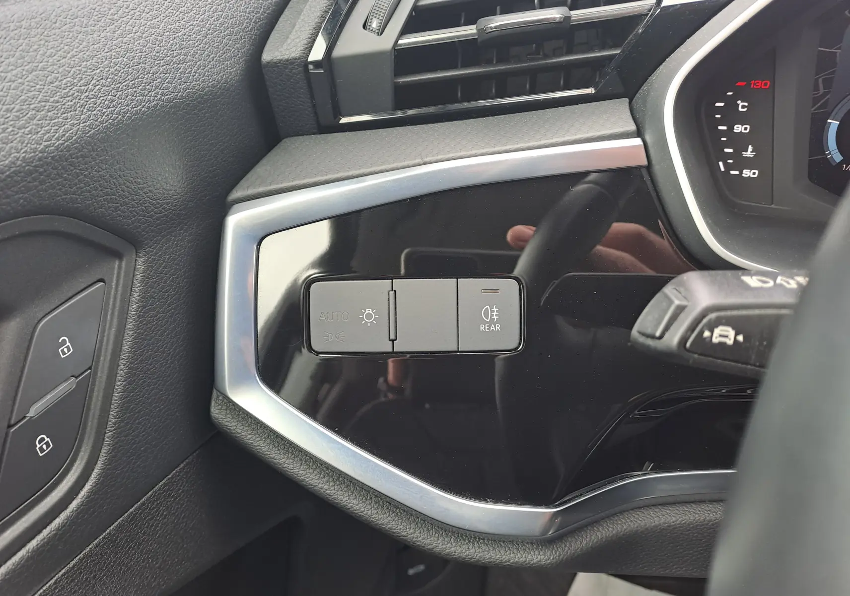 Gros plan sur les commandes d'éclairage à gauche du volant dans l'habitacle noir de l'Audi Q3 35 TDI 2023.
