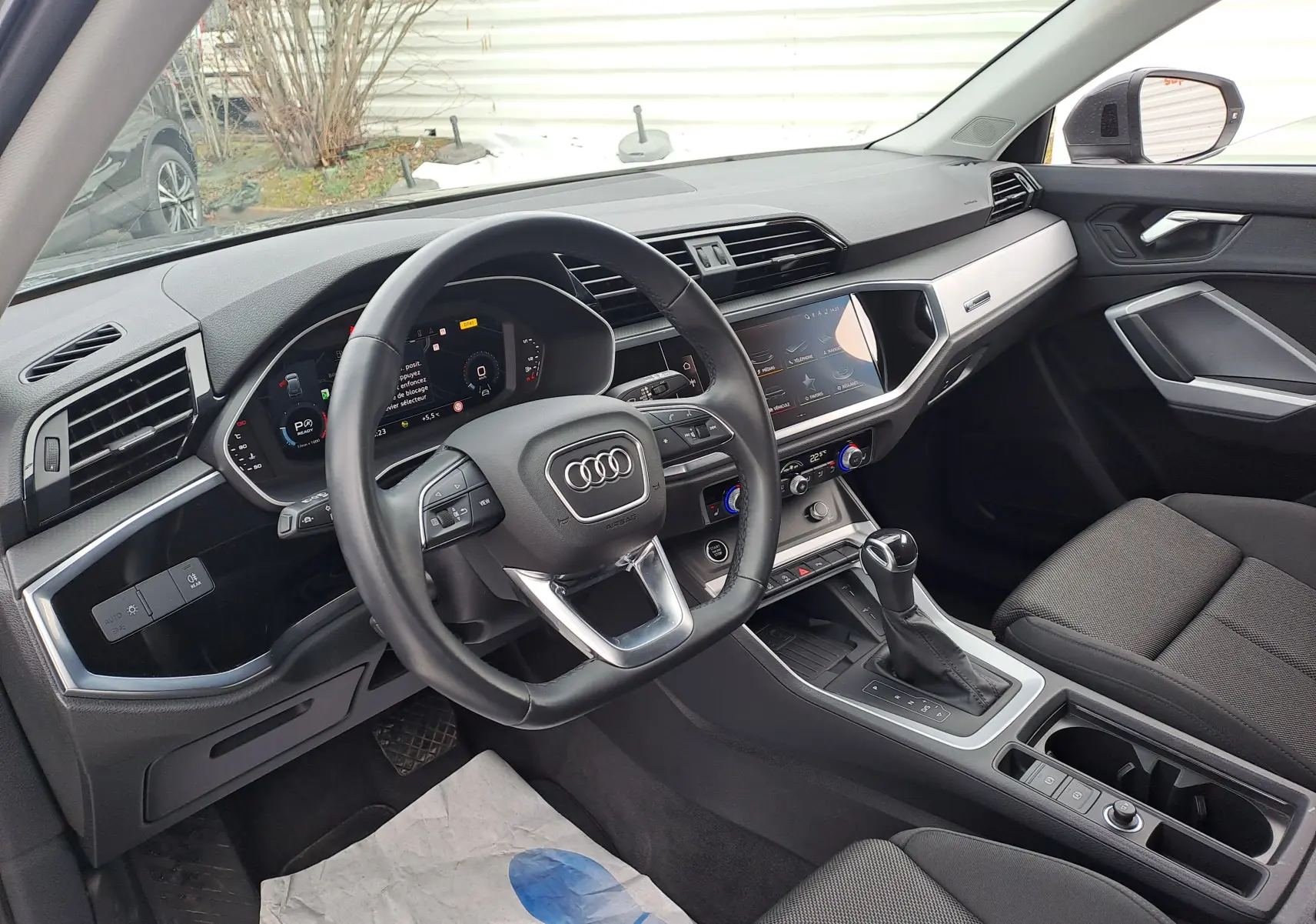 Intérieur noir de l'Audi Q3 35 TDI 2023 vu côté conducteur, avec tableau de bord digital et console centrale moderne.