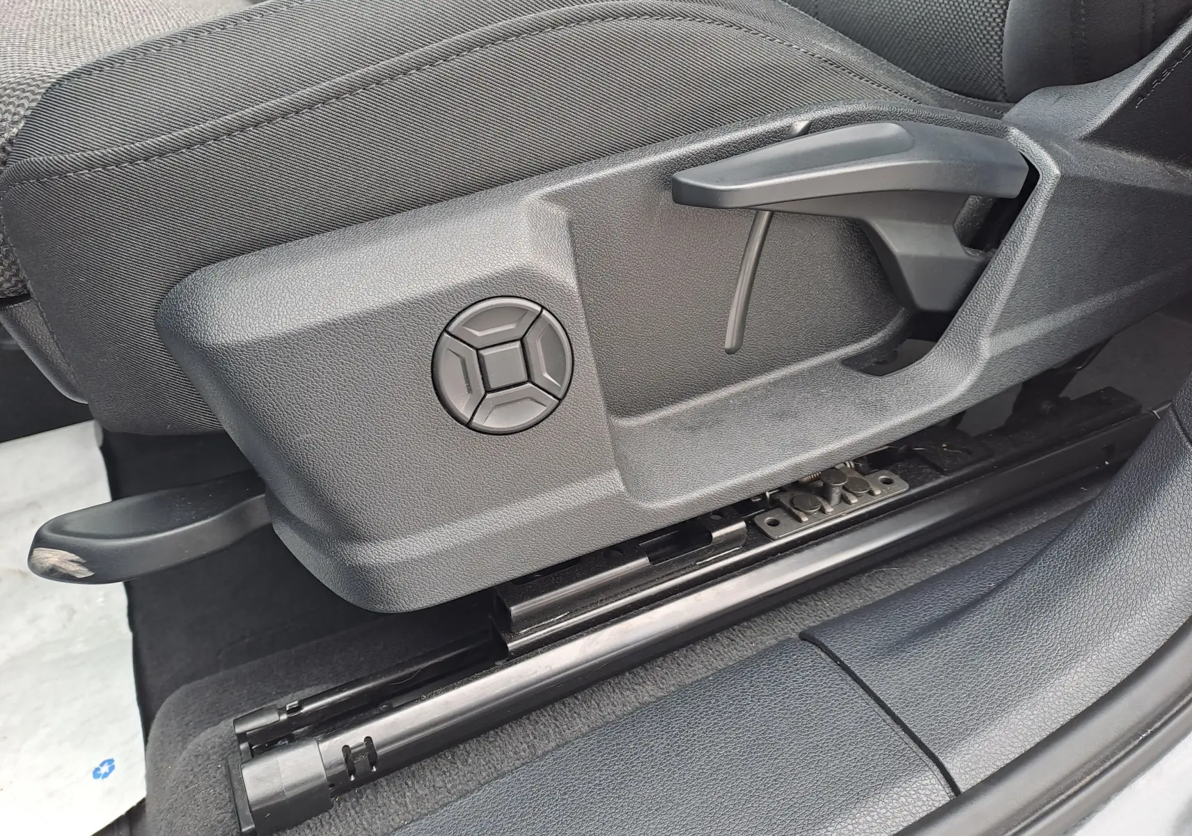 Détail du côté gauche du siège avant en tissu noir de l'Audi Q3 35 TDI 2023 avec commandes manuelles de réglage.