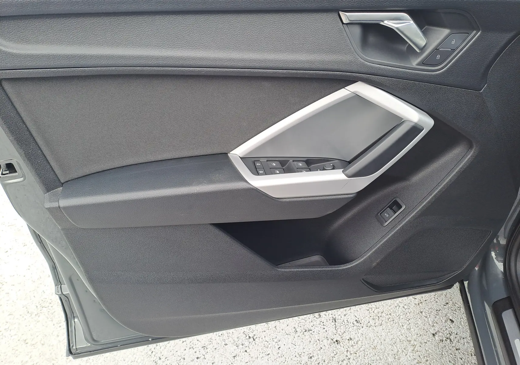 Vue intérieure côté gauche de la porte avant d’un Audi Q3 35 TDI gris nano avec commandes de vitres et serrure.