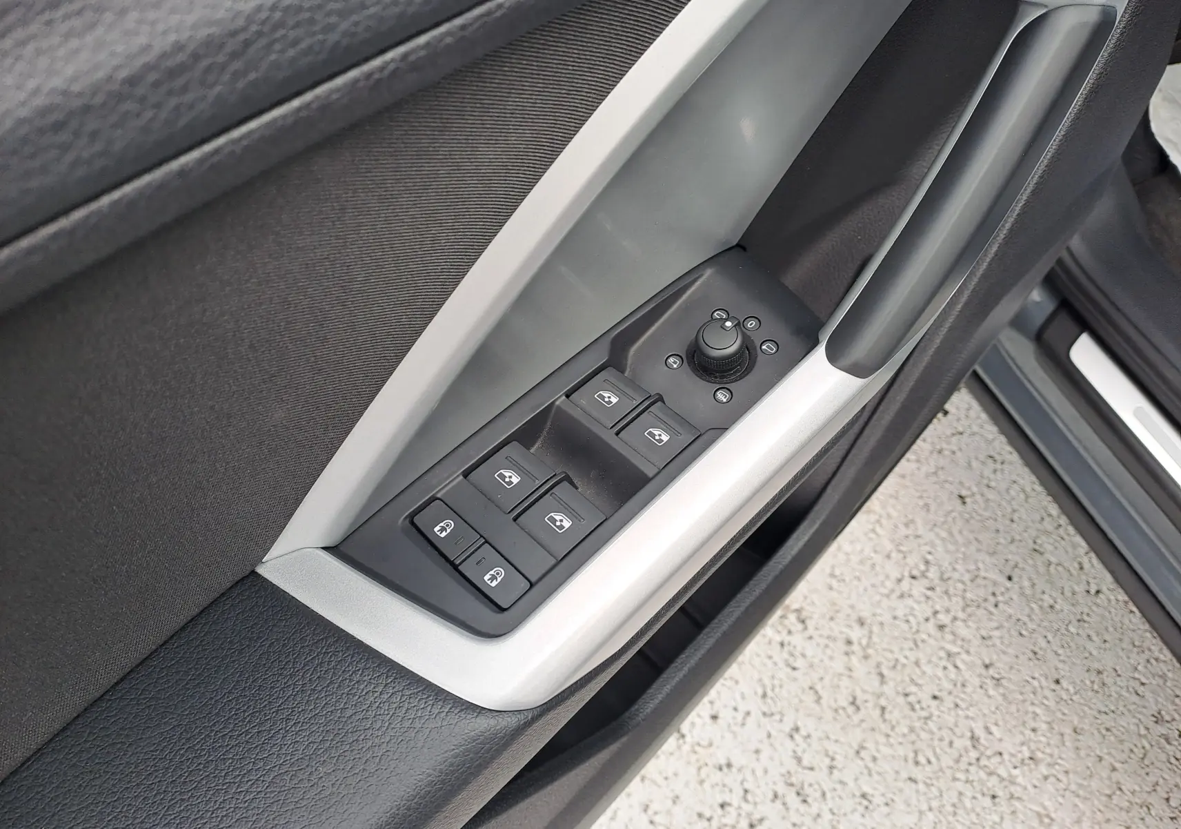Gros plan sur les commandes des vitres et rétroviseurs côté conducteur d’un Audi Q3 gris nano 2023.