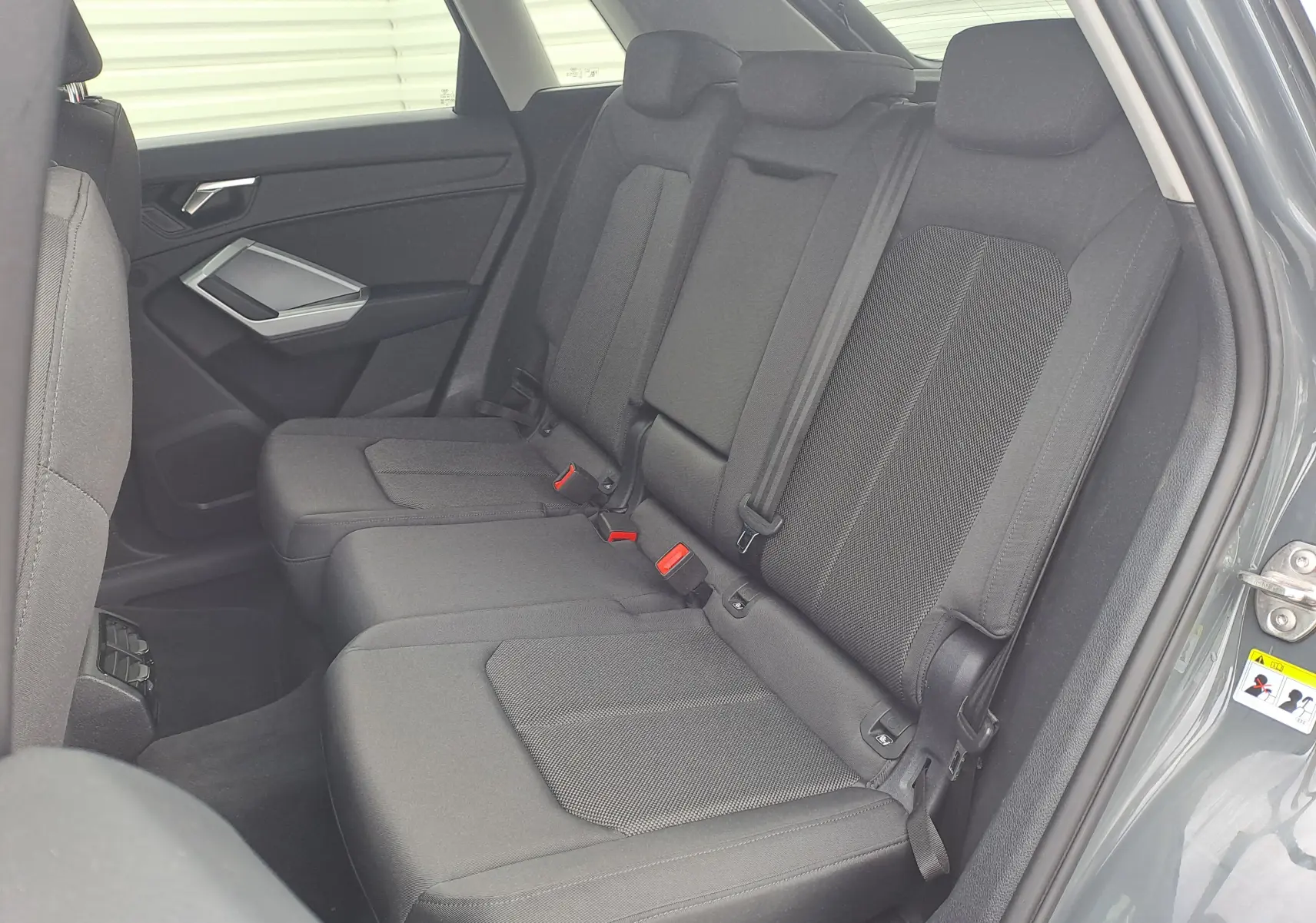 Vue intérieure côté droit montrant la banquette arrière en tissu noir du SUV Audi Q3 35 TDI 2023 gris nano.