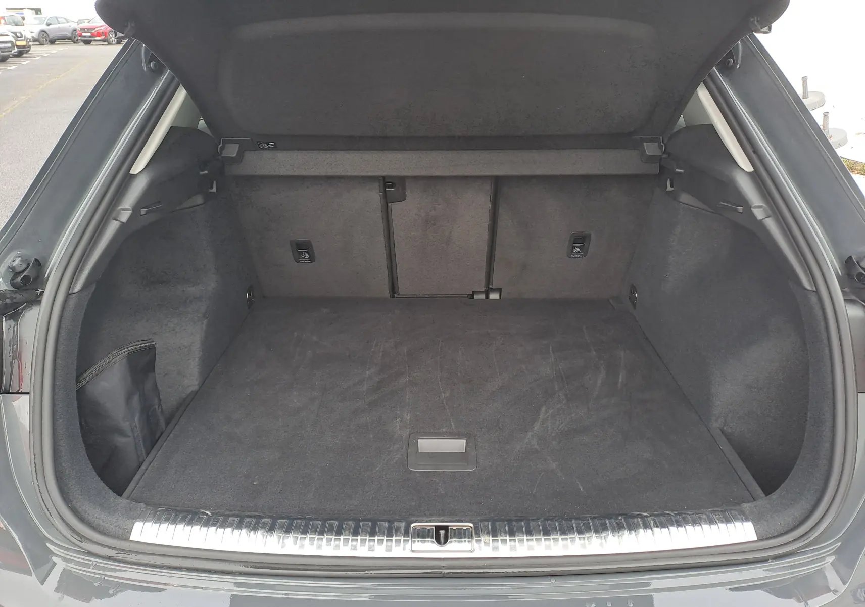 Coffre ouvert vu de l'arrière d'un Audi Q3 gris nano, montrant un espace de chargement propre et spacieux.