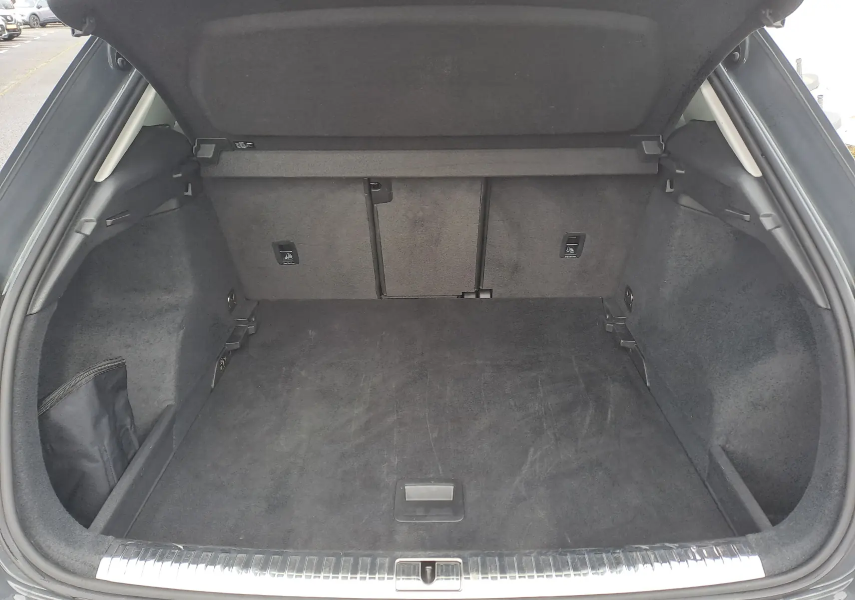 Coffre ouvert vu de l'arrière d'un Audi Q3 35 TDI gris nano, montrant un espace de chargement propre et spacieux.