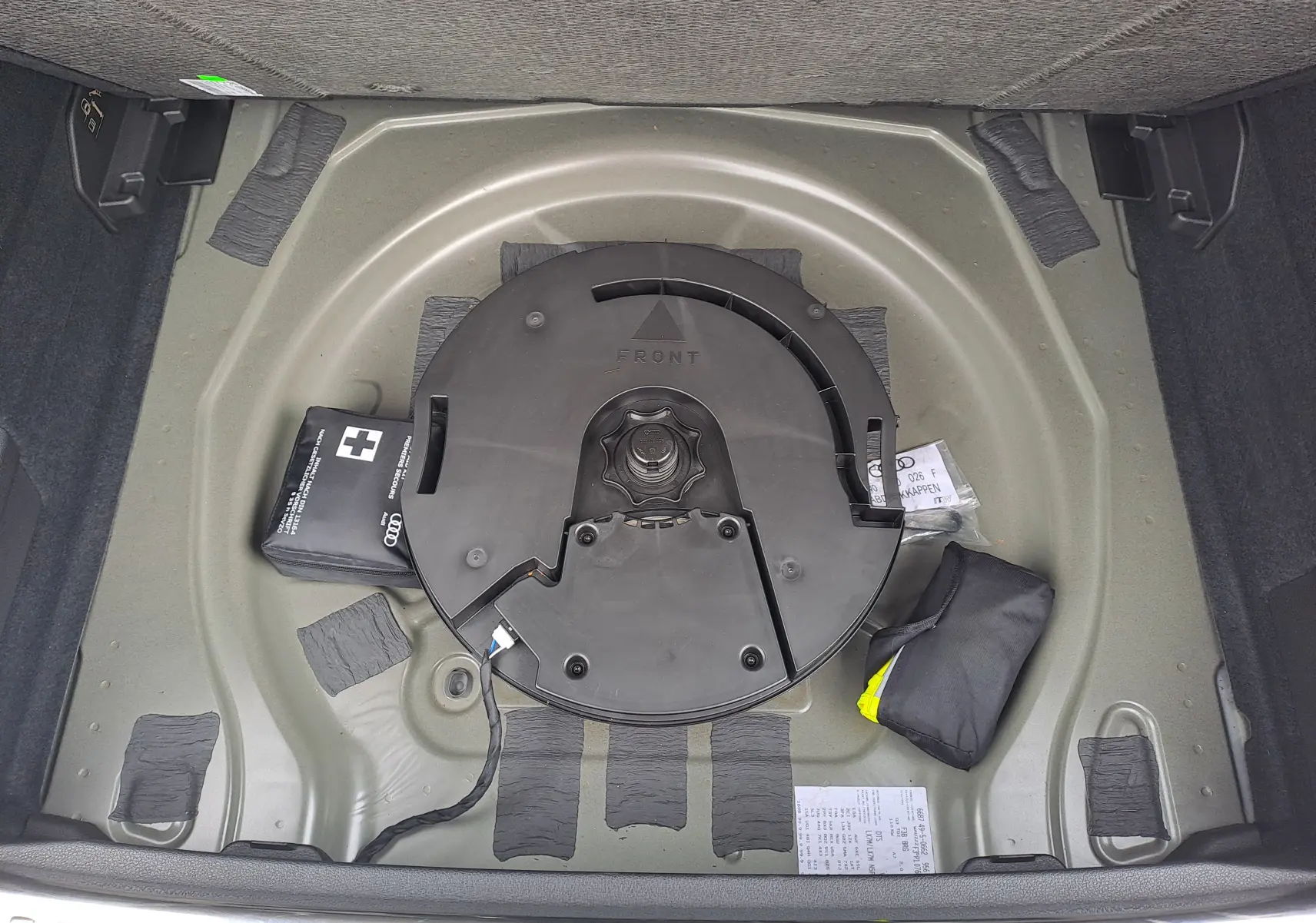 Vue plongeante sur le coffre nu d’un Audi Q3 gris nano, montrant le rangement sous la roue de secours.