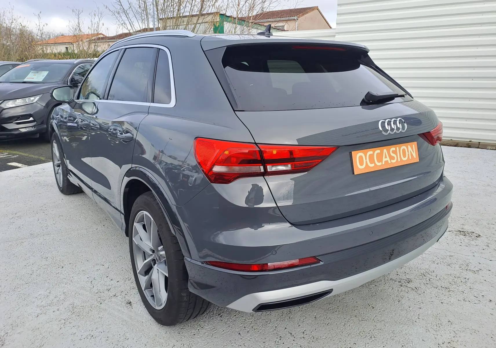 Vue 3/4 arrière droite d'un Audi Q3 gris nano 2023 avec jantes alu 19 pouces et feux arrière LED.