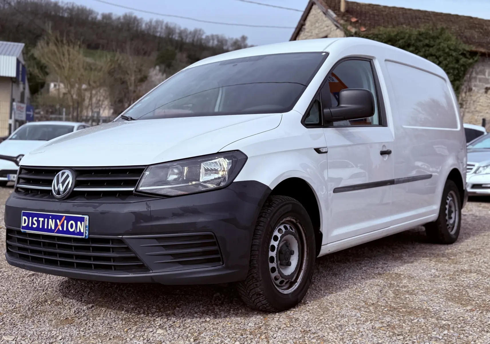 Vue 3/4 avant droit d’un utilitaire Volkswagen Caddy Maxi Long blanc avec pare-chocs noir et jantes acier.