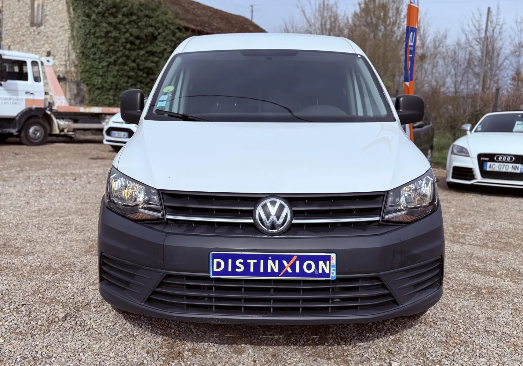 Vue de face d’un Volkswagen Caddy Maxi Long blanc avec pare-chocs noir et plaque Distinxion visible.