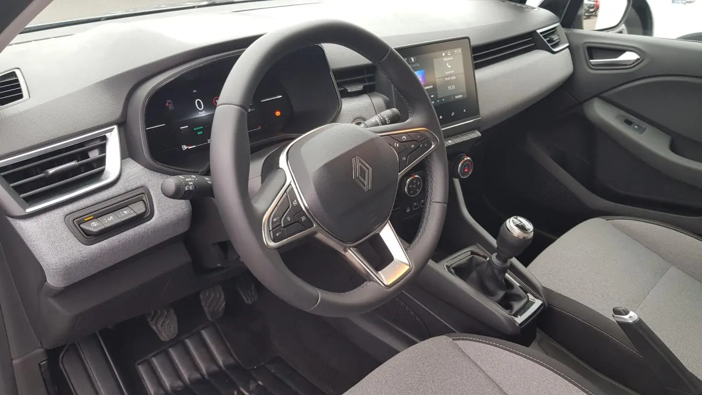 Vue intérieure côté conducteur de la Renault Clio gris 2025, avec volant multifonction et boîte manuelle visible.