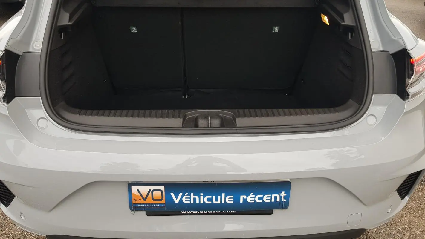 Coffre ouvert vu de l'arrière d'une Renault Clio gris clair 2025 avec feux arrière et pare-chocs visibles.
