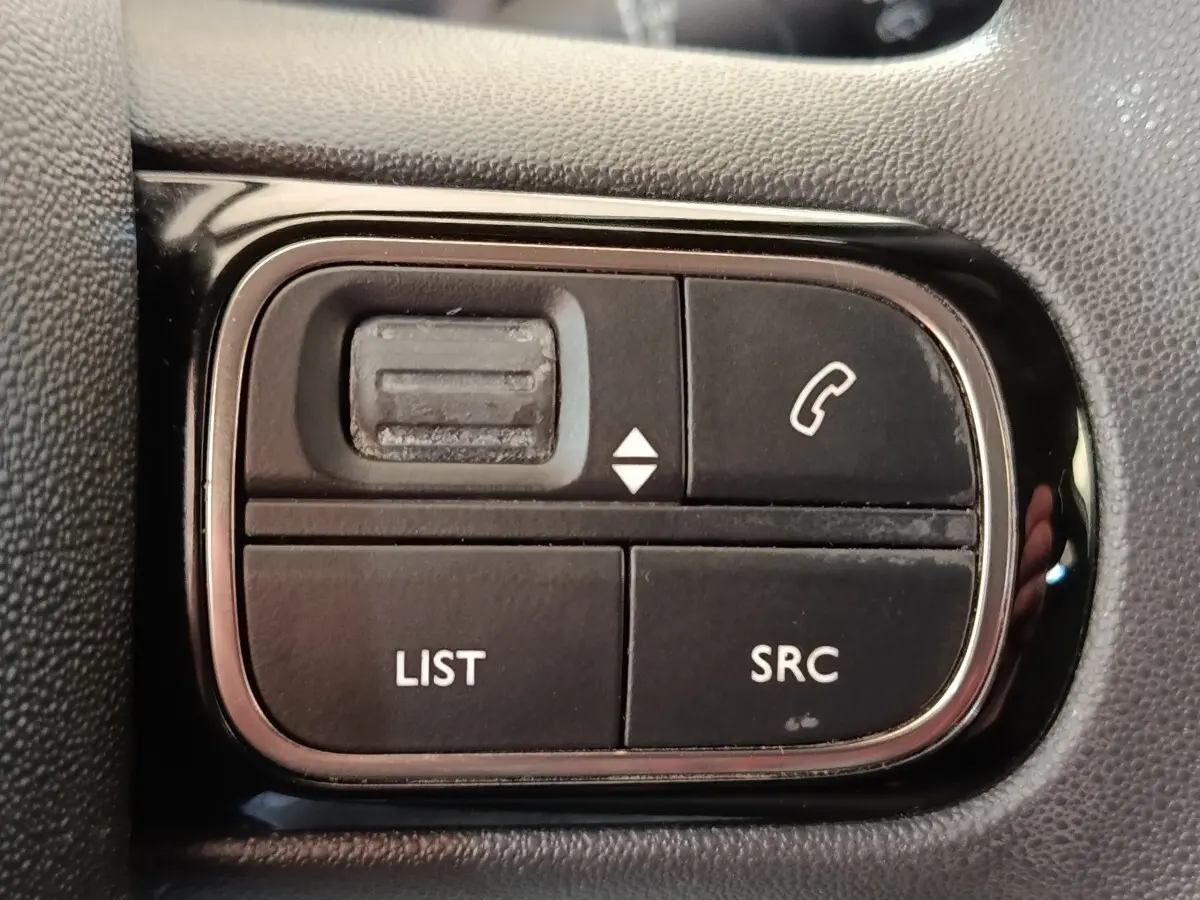 Gros plan sur les commandes noires du volant multifonctions de la Citroën C3 blanche de 2022.