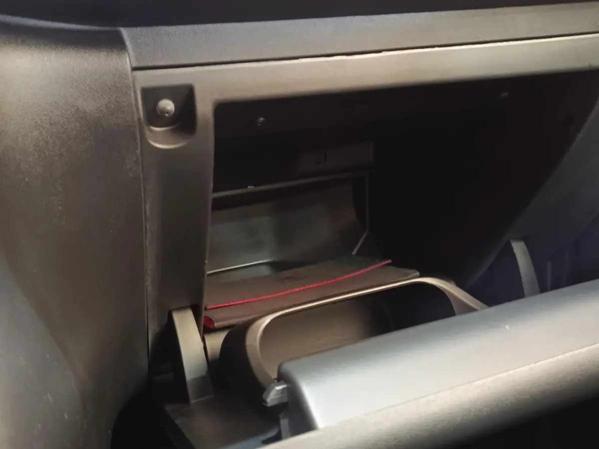 Gros plan sur la boîte à gants ouverte de la Citroën C3 blanche, montrant un rangement intérieur avec un livret.