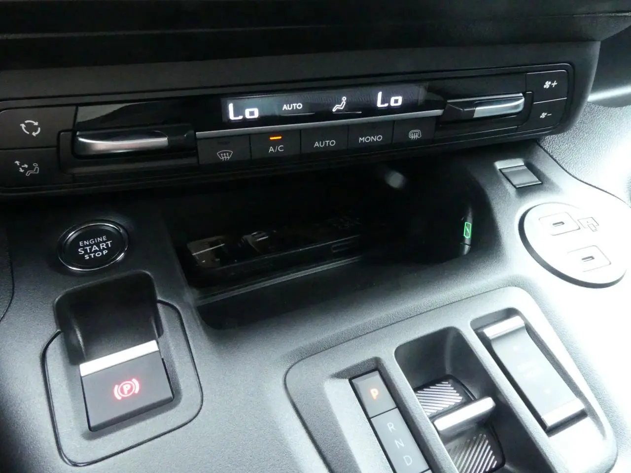 Détail de la console centrale du Peugeot Partner 2025 avec commandes climatisation, bouton start/stop et boîte auto compacte.