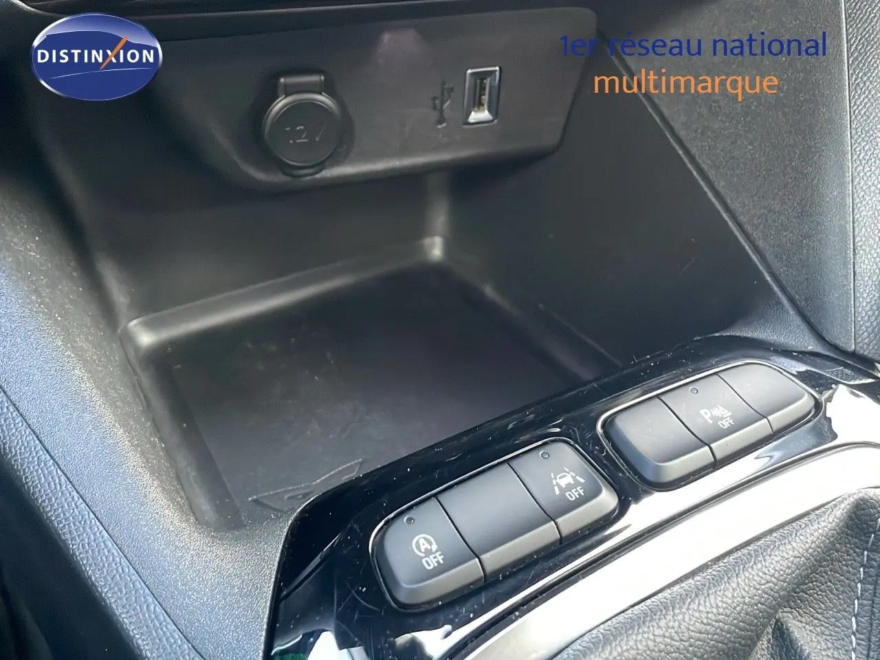 Vue rapprochée de la console centrale de l’Opel Corsa gris Kristall Metal montrant les boutons de contrôle et prise 12V.