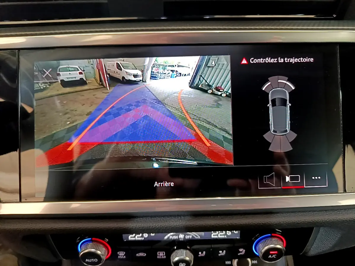 Écran tactile affichant la caméra de recul et l'aide au stationnement du tableau de bord de l'Audi Q3 noir 2021.