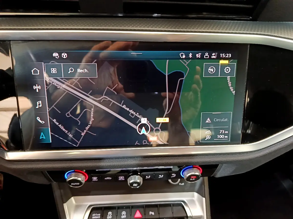 Écran tactile central du tableau de bord de l'Audi Q3 35 TDI noir, affichant la navigation GPS en vue satellite.