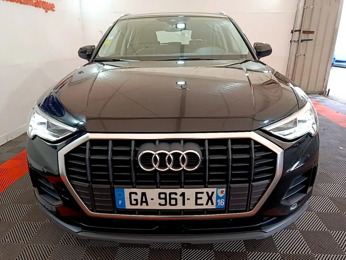 Vue frontale d'un Audi Q3 noir 35 TDI 150 S tronic Business Line avec calandre hexagonale et phares LED allumés.