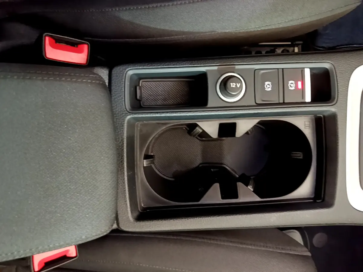 Gros plan sur la console centrale noire de l'Audi Q3 35 TDI 2021 avec porte-gobelets et prise 12V visible