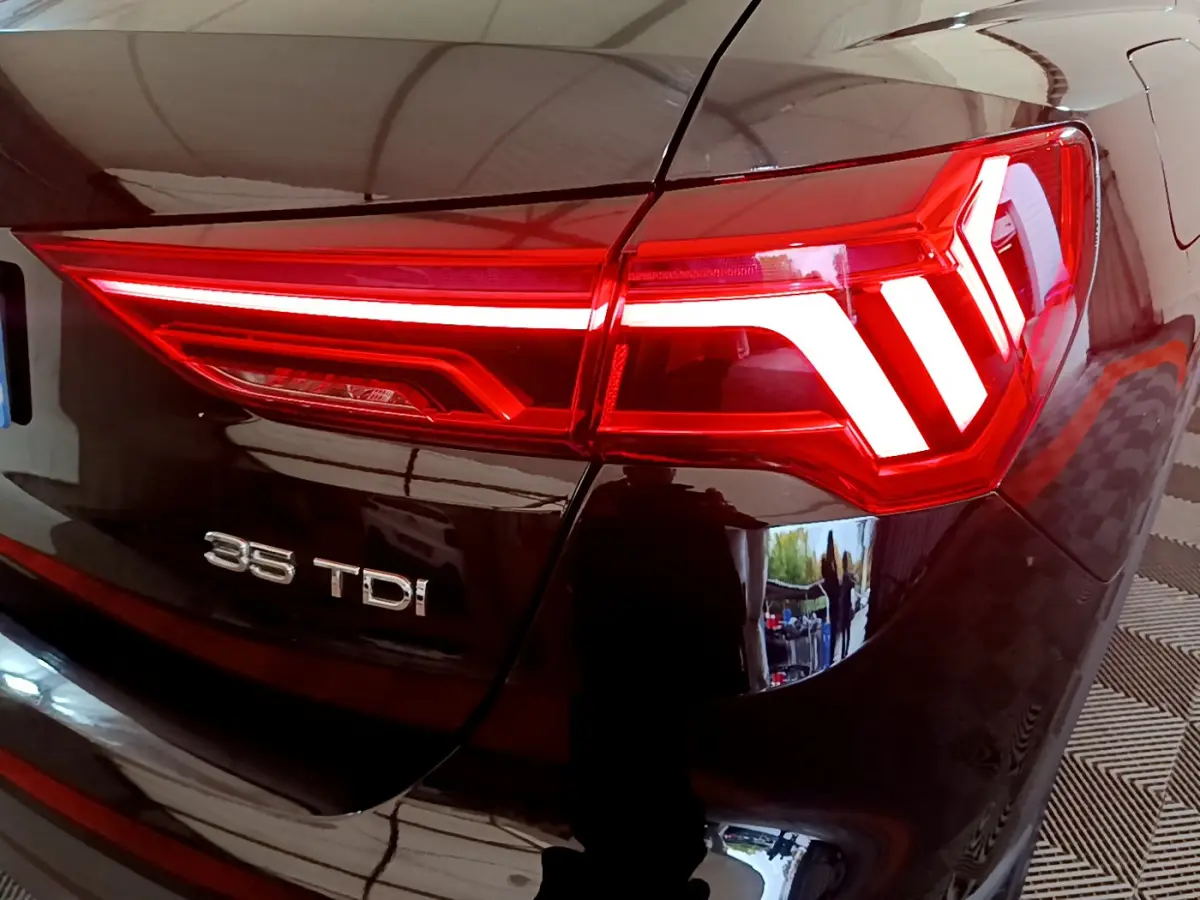 Gros plan sur le feu arrière droit rouge et l’inscription 35 TDI du coffre noir d’un Audi Q3 2021.