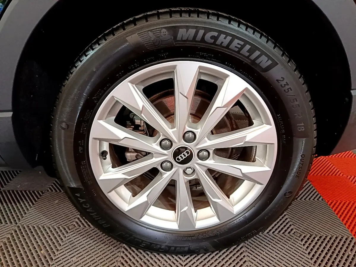 Gros plan sur la jante en alliage argentée avec logo Audi et pneu Michelin du SUV noir Audi Q3 2021.