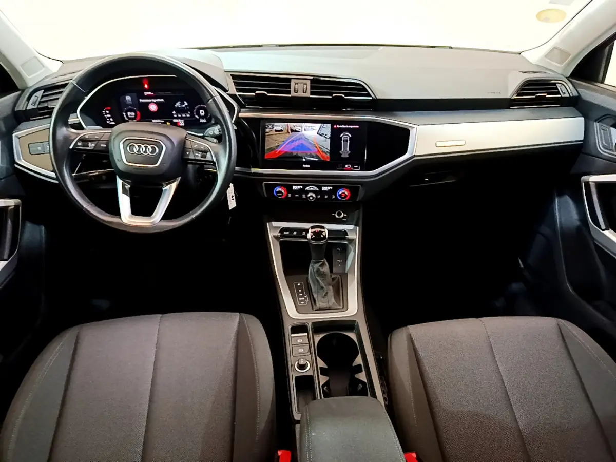 Intérieur Audi Q3 35 TDI 2021 vu de face, tableau de bord moderne avec écran tactile et volant cuir noir.