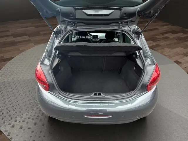 Vue arrière ouverte de la Peugeot 208 gris platinium, coffre vide et banquette arrière visible à l'intérieur.