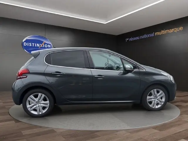 Profil droit d'une Peugeot 208 gris platinium 2017 en intérieur, avec jantes alliage et vitres teintées.