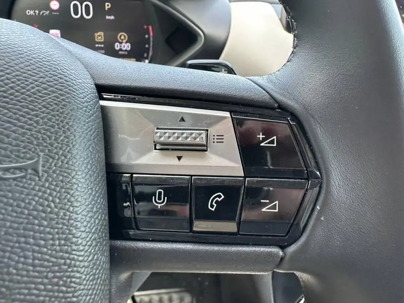 Gros plan sur les commandes de volume et téléphone au volant d’une DS3 2024, finition Esprit Voyage, intérieur noir.